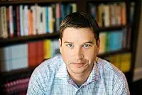 Foto do escritor Cal Newport em frente a uma estante de livros
